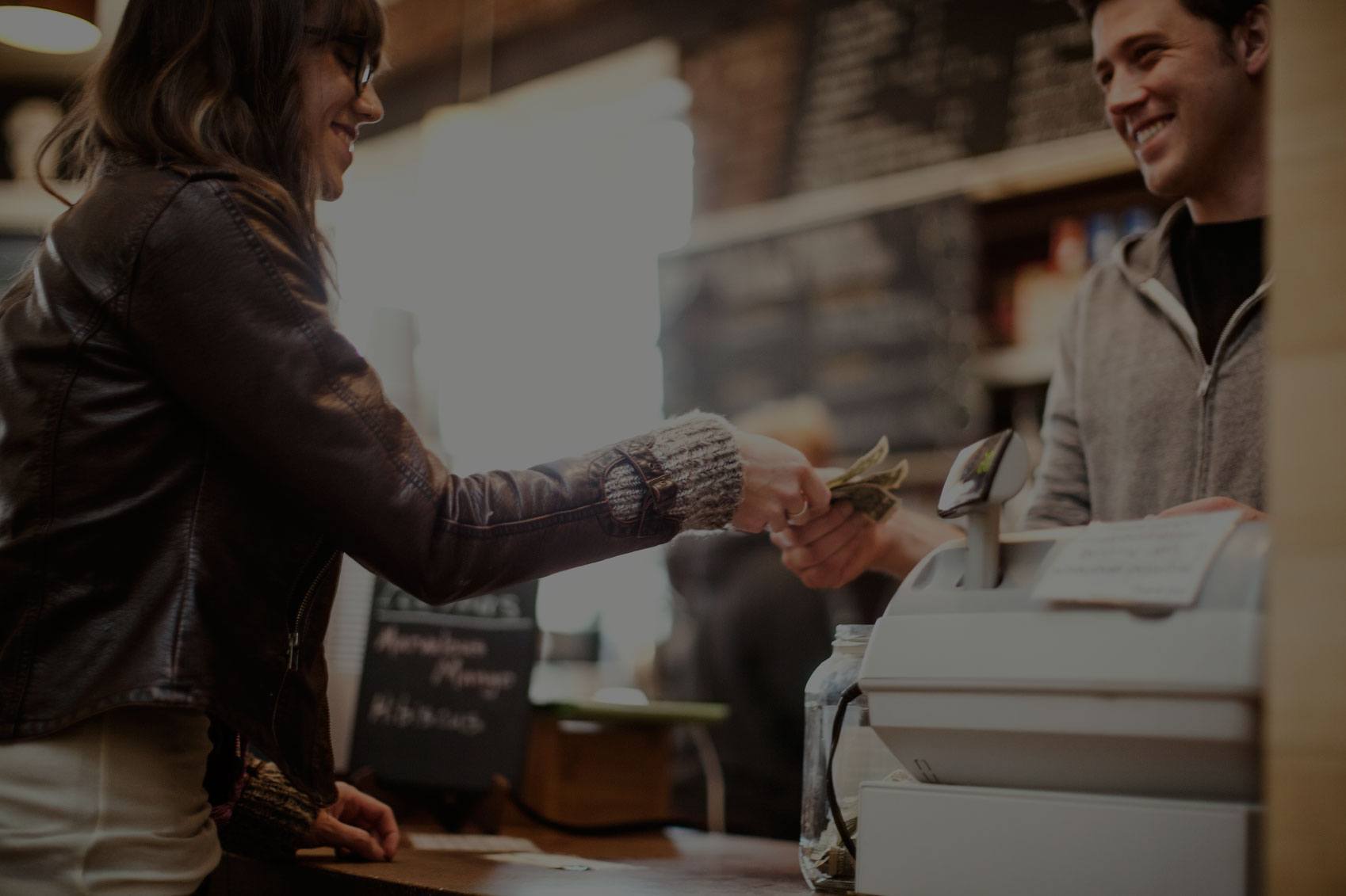 A woman at a cafe counter handing over money to make a purchase.